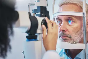 Older man receiving an eye exam with slit lamp diagnostic equipment.